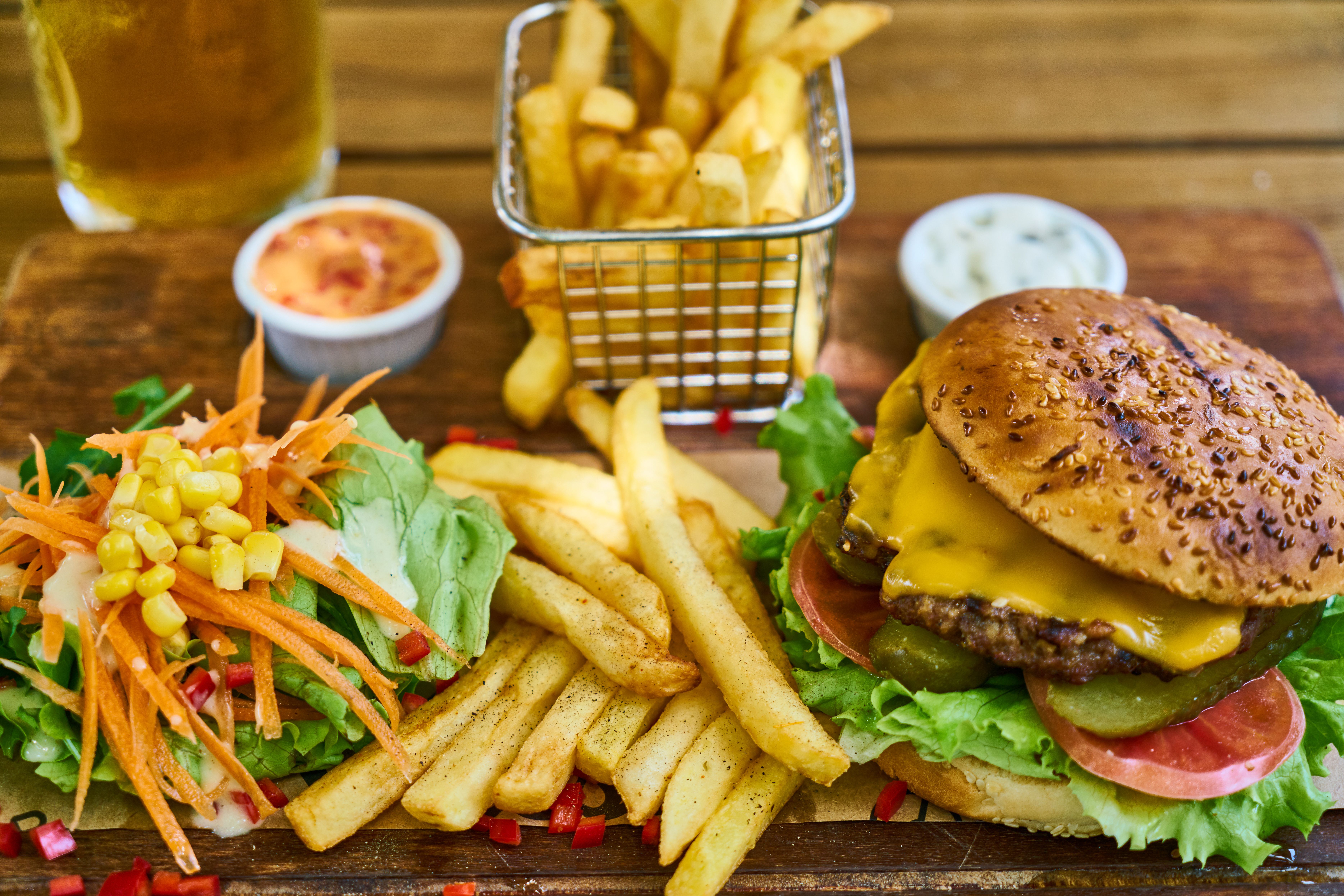Hamburguesa con papas fritas y ensalada sobre una mesa